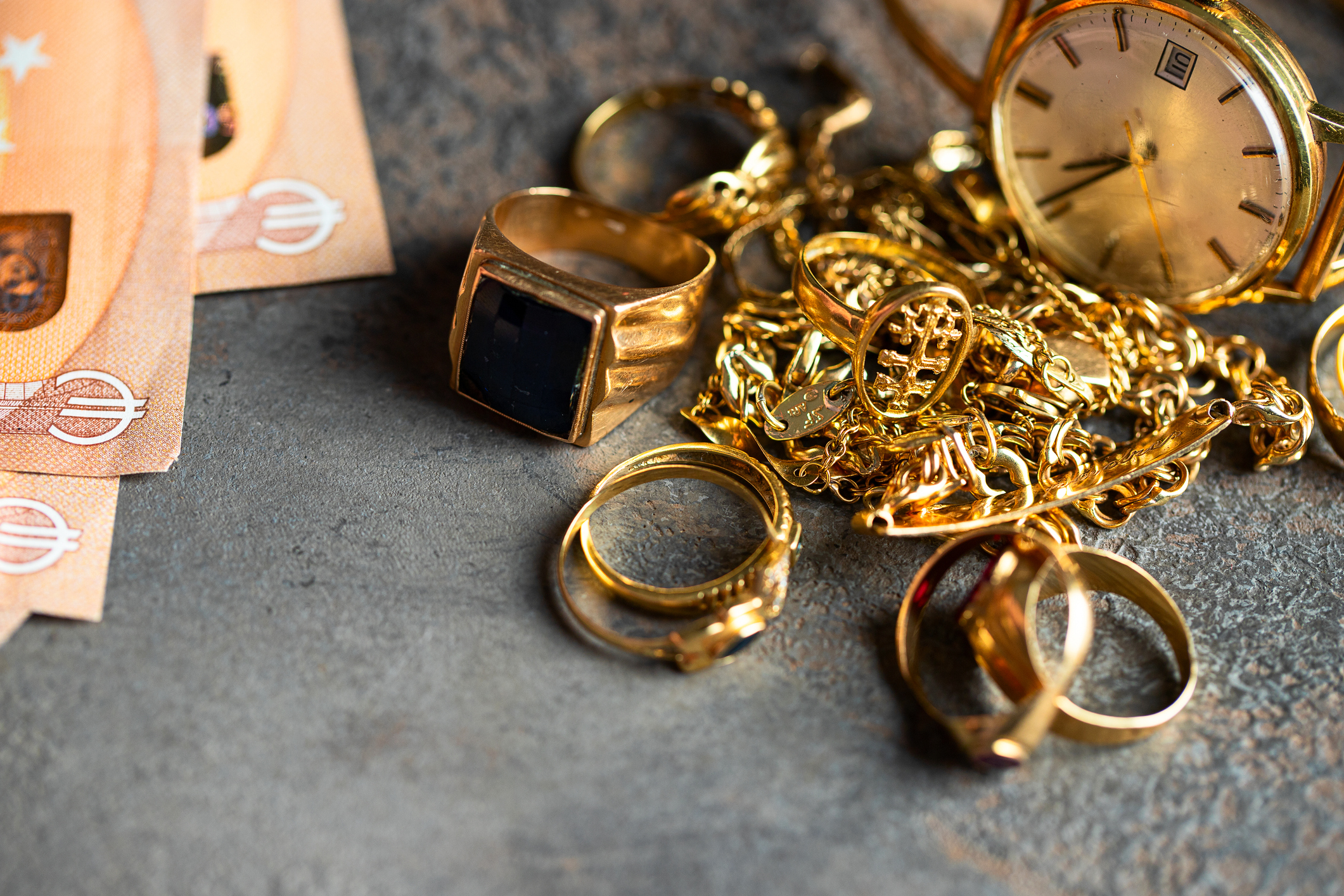 Old and broken jewelry and on Euro banknotes on dark background. Sell gold for money concept. Old and broken jewelry and on Euro banknotes on dark background. Sell gold for money concept.